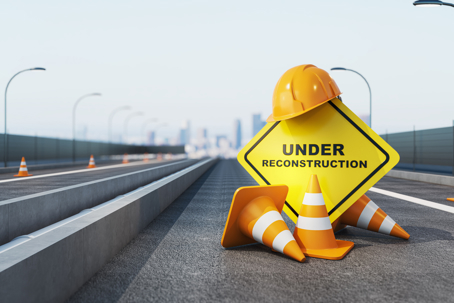 oad under construction with cones, helmet and warning sign in realistic style on light urban background, concept of repair,