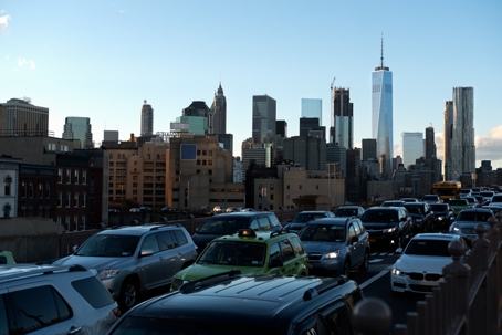 Cars drive in bumper-to-bumper traffic with the Manhattan skyline visible in the background. | Gannes & Musico, LLP
